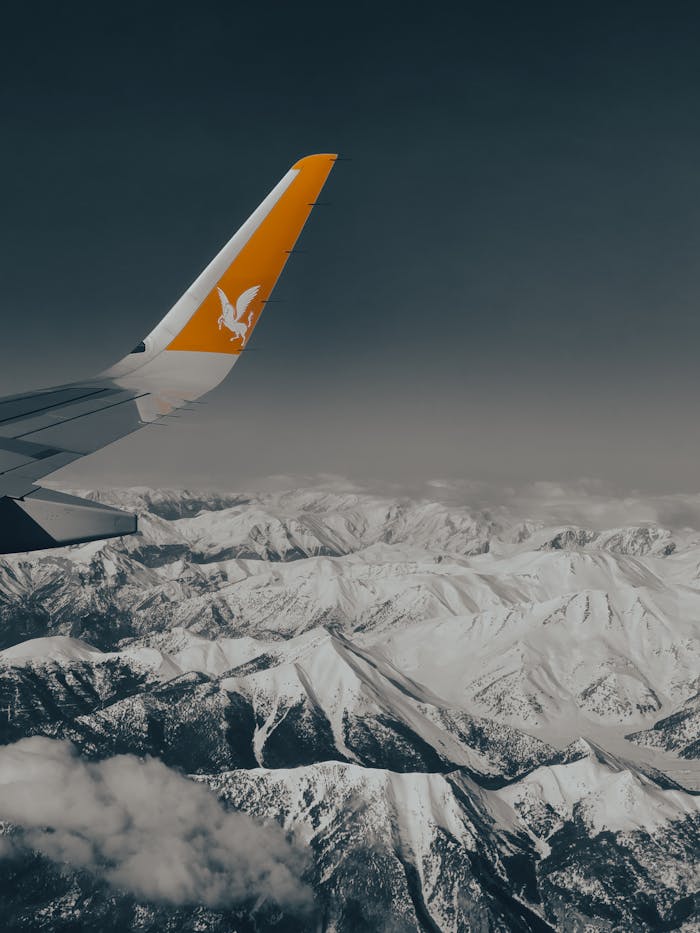 An airplane flies over snowcapped mountains, showcasing a serene aerial perspective.